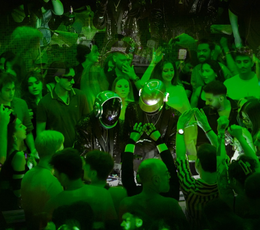 ALIVE behind the decks in green light as the crowd cheers
